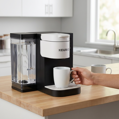 A Keurig K-2500 coffee brewer with a large reservoir on a kitchen counter, with a person holding a mug under the dispenser for scale.