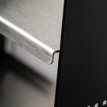 A detailed macro photograph showing the high-quality junction of the brushed stainless steel shelf and the textured matte black powder-coated side panel of the RAKABOT Signature shoe rack.