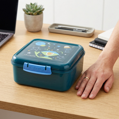 A scale-reference shot showing the specific Sistema lunch cube beside an open adult hand, emphasizing its actual size.