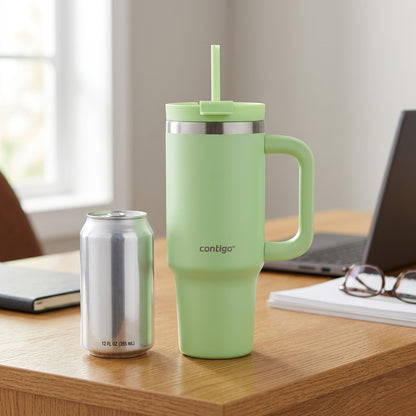 A lime-green Contigo 30 oz tumbler stands next to a standard 12 oz aluminum soda can on a wood desk.